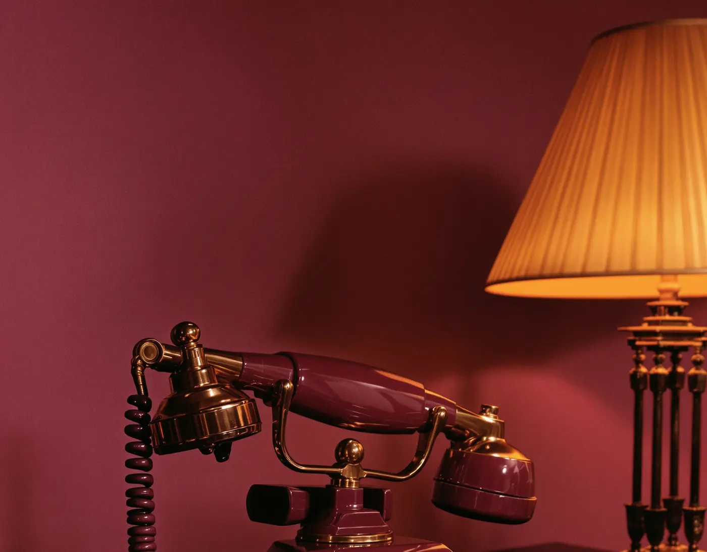A 1930s plum bakelite telephone with brass trim, its handset resting and lamp lit